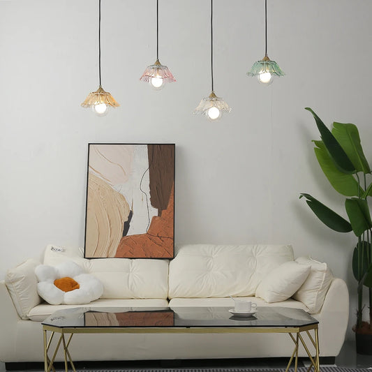 A living room scene featuring a white sofa, a coffee table, and a wall painting, with four colorful glass pendant lights hanging above.