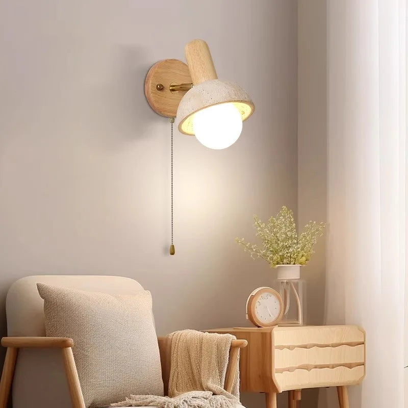 Natural stone dome shade wall sconce with a wooden arm and pull chain, mounted on a wall next to a chair.
