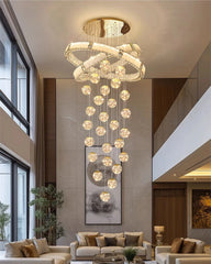 Luxury chandelier hanging in a modern living room with large windows and a sofa.