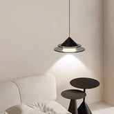 A modern black tiered pendant light with a frosted glass diffuser hangs over a bedside table.