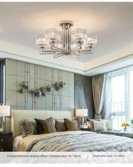 A polished chrome multi-arm crystal chandelier installed in a bedroom with a large bed.