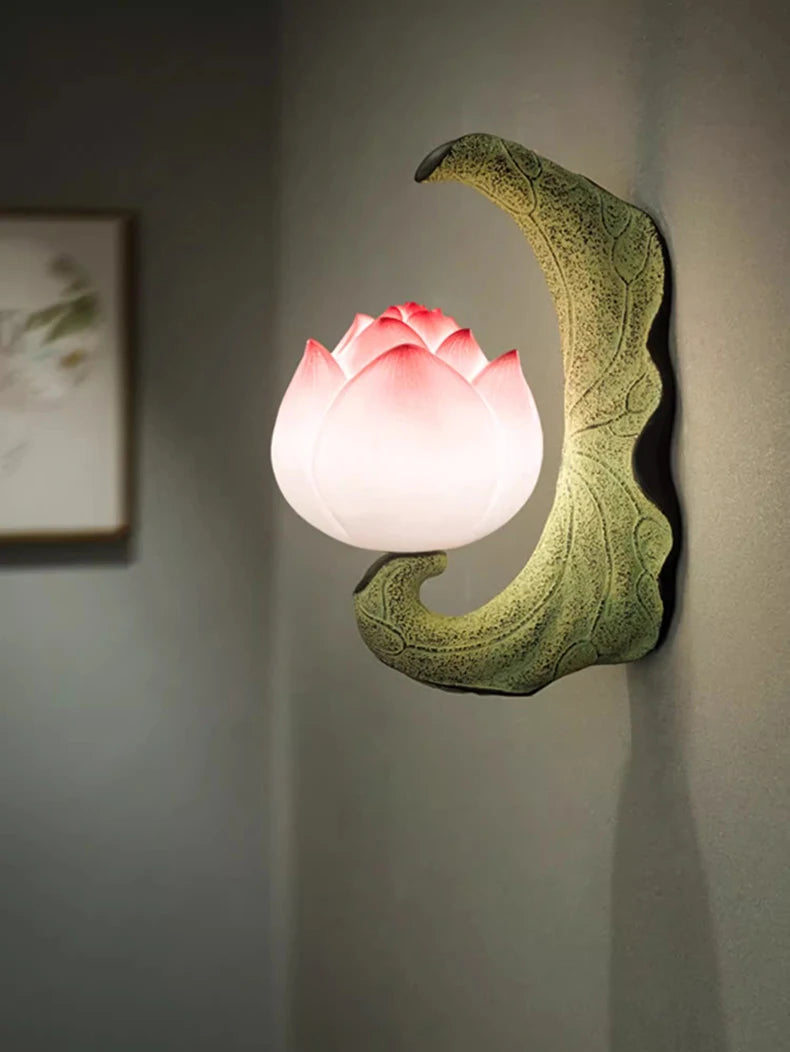 Decorative wall lamp shaped like a lotus flower with a pink light on a gray wall.