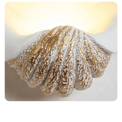 Shell-shaped wall light fixture with a textured surface on a white background