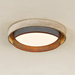 Close-up of a circular flush mount ceiling light with a textured, stone-like outer ring and a perforated metal band, emitting a warm light.