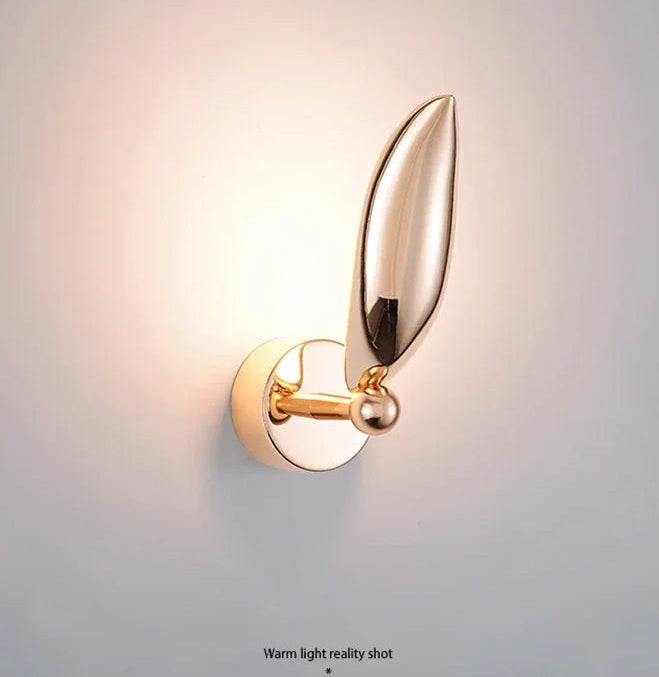Gold wall sconce with leaf design on a light gray background