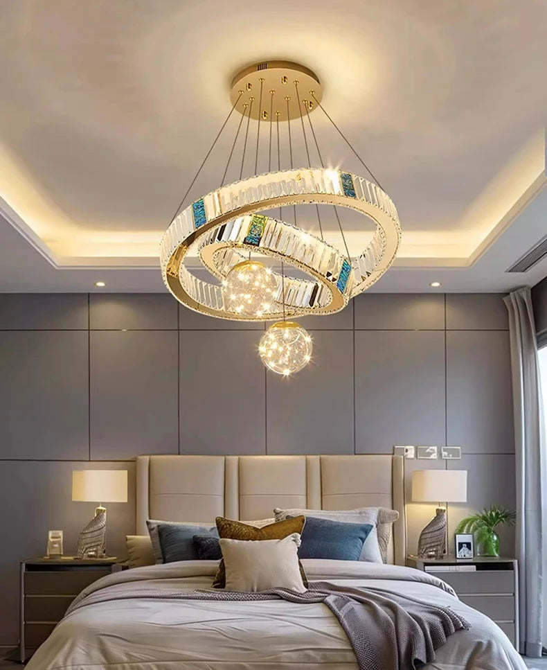 Modern chandelier hanging above a bed in a bedroom with gray walls.