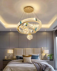 Modern chandelier hanging above a bed in a bedroom with gray walls.