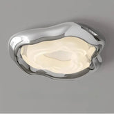 Close-up of a modern chrome ceiling light with an organic, wavy design and a diffused light source.