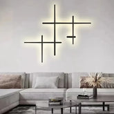 Cluster of black geometric line wall lights mounted on a white wall above a light-colored sofa.