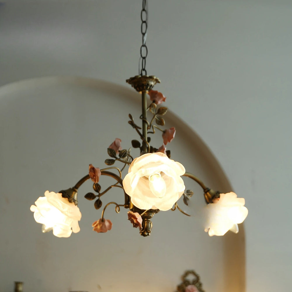 A brass chandelier with illuminated frosted glass shades, showcasing its floral design.