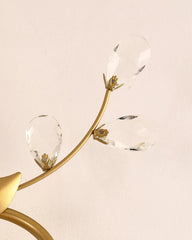 Decorative wall light fixture with gold arm and clea on a beige background