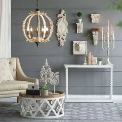 A living room scene featuring a distressed white carved wood globe chandelier hanging above a coffee table with decorative items.