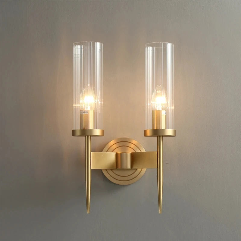Gold wall sconce with clear glass shades on a gray background