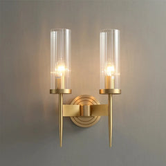 Gold wall sconce with clear glass shades on a gray background
