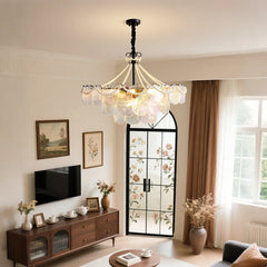 A living room scene featuring a glass tiered chandelier with pearl accents, a television, wooden furniture, and patterned doors.