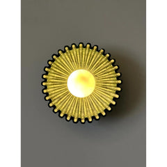 Circular wall sconce with radiating gold elements and a central warm LED bulb.