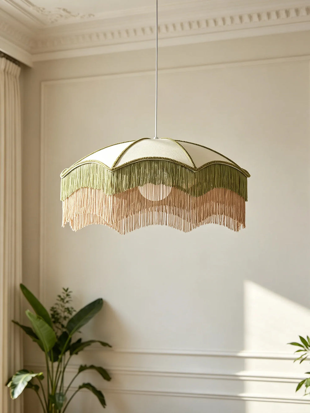 Close-up of a white fabric umbrella pendant light with layered green and pink fringe, illuminated.