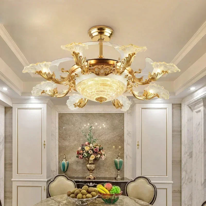 An angled view of a gold ceiling fan light featuring a central glass diffuser and intricate floral crystal arms, illuminating a dining area.