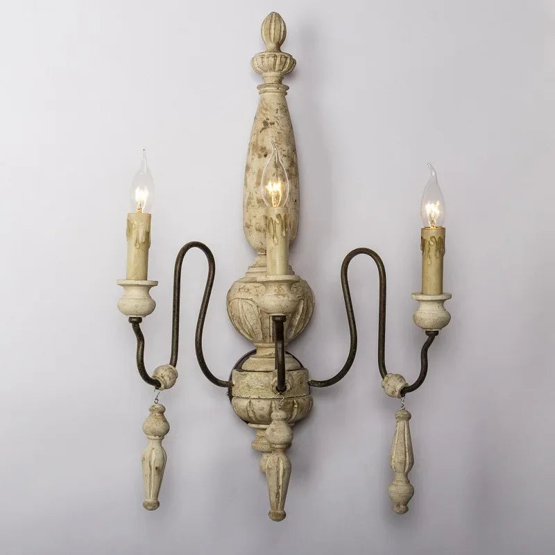Decorative wall sconce with three candle-style lights on a plain background