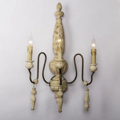 Decorative wall sconce with three candle-style lights on a plain background