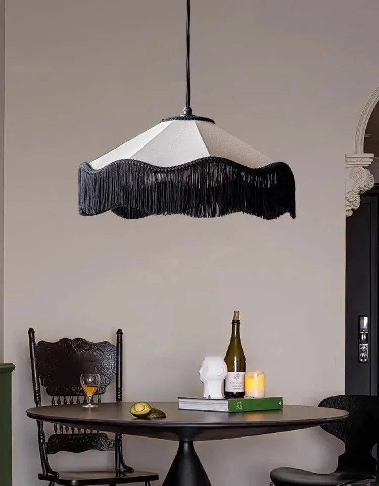 Modern pendant light with black fringe shade hanging above a dining table.