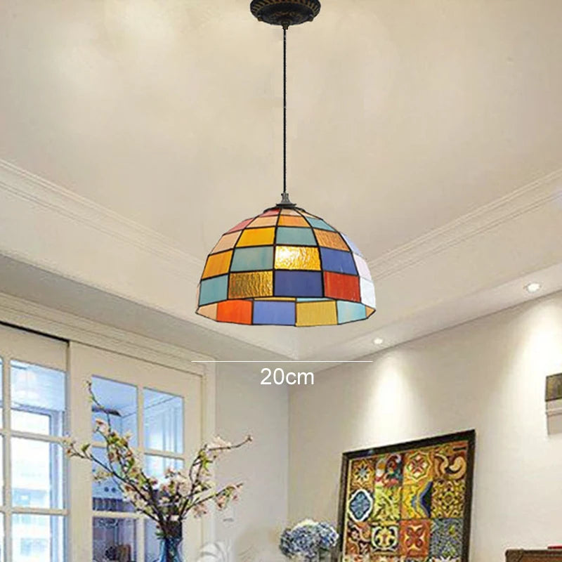 A colorful, geometric Tiffany-style pendant light with a dome shade suspended from the ceiling in a well-lit room.