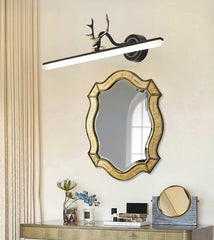 Decorative wall mirror with gold frame and modern light fixture on a beige wall.