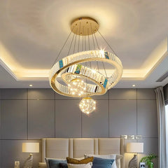 Modern chandelier in a bedroom setting with gray walls and a bed.