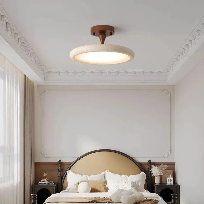 A bedroom scene featuring a dark wood and stone textured ceiling light fixture, with decorative elements on the wall and bed.