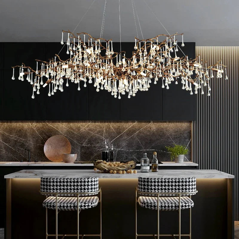 Modern kitchen with a long, cascading brass chandelier with clear teardrop crystals and black and white patterned bar stools.