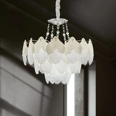 White glass leaf tiered chandelier against a dark background