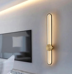 Modern wall-mounted light fixture on a white wall next to a television.