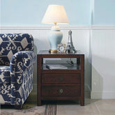 A light blue ceramic table lamp with a cream drum shade sits on a dark wood side table next to a sofa.