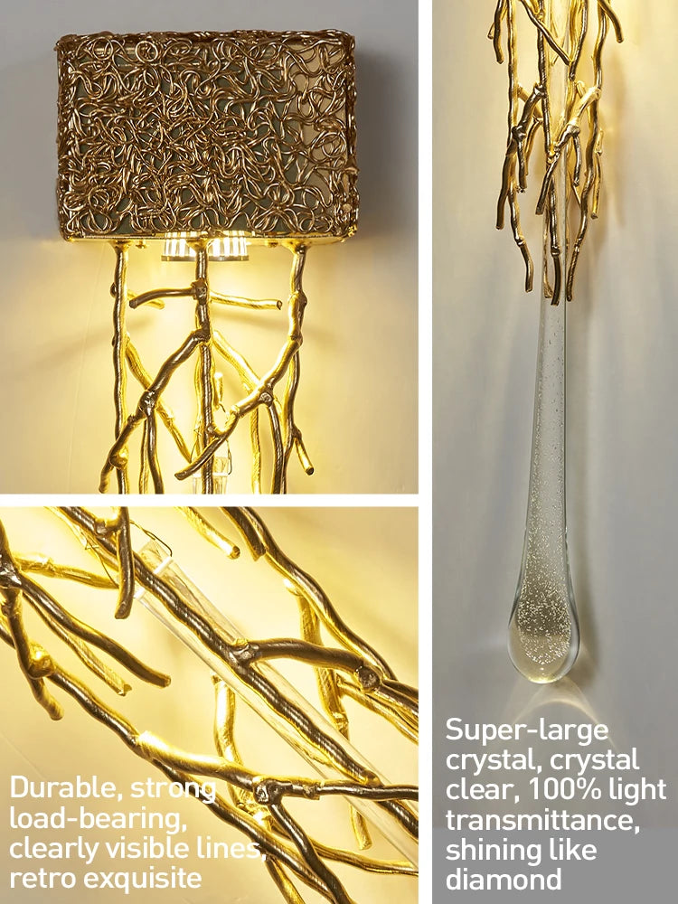 Decorative wall light fixture with gold branch-like design and crystal clear glass shade.