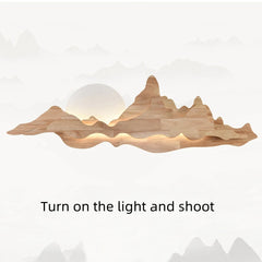 Wooden mountain-shaped wall light with a glowing interior on a white background