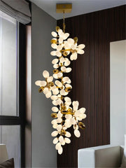 Decorative chandelier with white floral lights and gold accents in a modern interior setting.