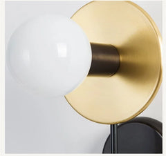 Gold wall sconce with a white bulb on a light gray background