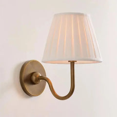 Wall-mounted lamp with a white shade and brass fixture on a light background