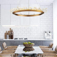 Modern kitchen with a gold pendant light fixture, white tiled walls, and a dining table with fruit.