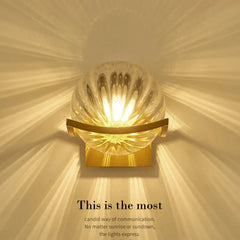 Decorative wall light with a gold frame and glass shade on a beige background.