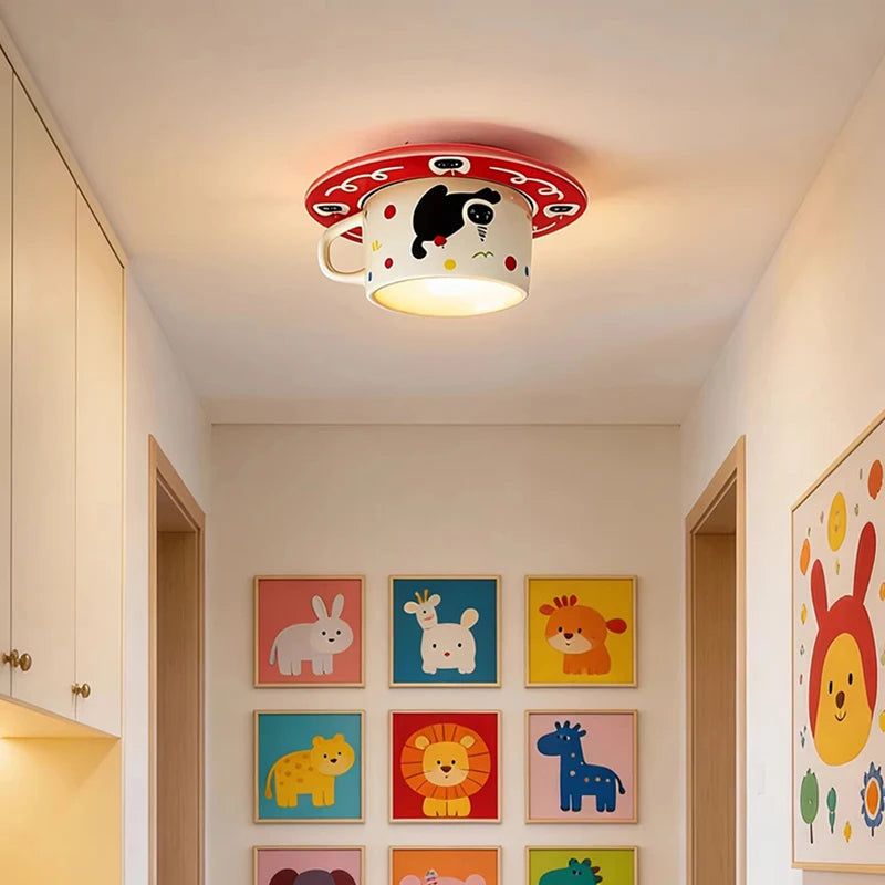 A red ceramic coffee cup shaped ceiling light installed in a hallway with animal art on the walls.