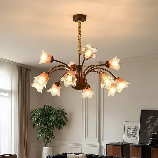 Bronze floral bud chandelier pendant light with clear glass shades illuminated in a room.