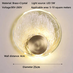 Wall-mounted light fixture with brass and crystal design, featuring LED lighting details.