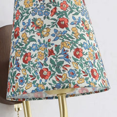 Floral-patterned lampshade on a gold stand against a white background