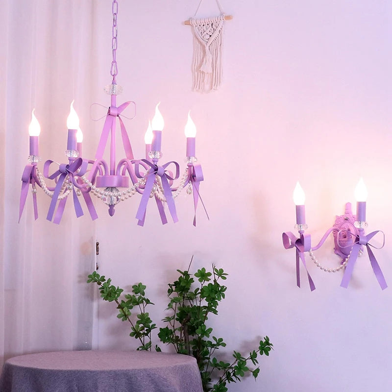 A room scene showing a purple chandelier and a matching purple bow candle-style wall sconce on the wall.