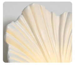 Shell-shaped decorative light fixture with a textured surface on a gray background