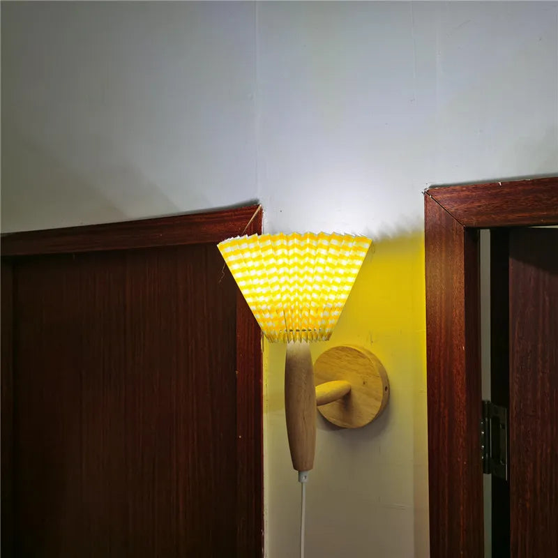 Wall-mounted lamp with yellow glass shade and wooden base on a white wall.