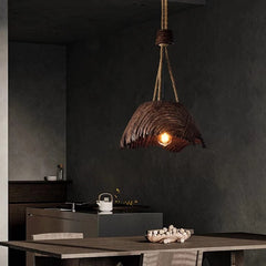 Wooden pendant light hanging in a dark room with a table and decor items.