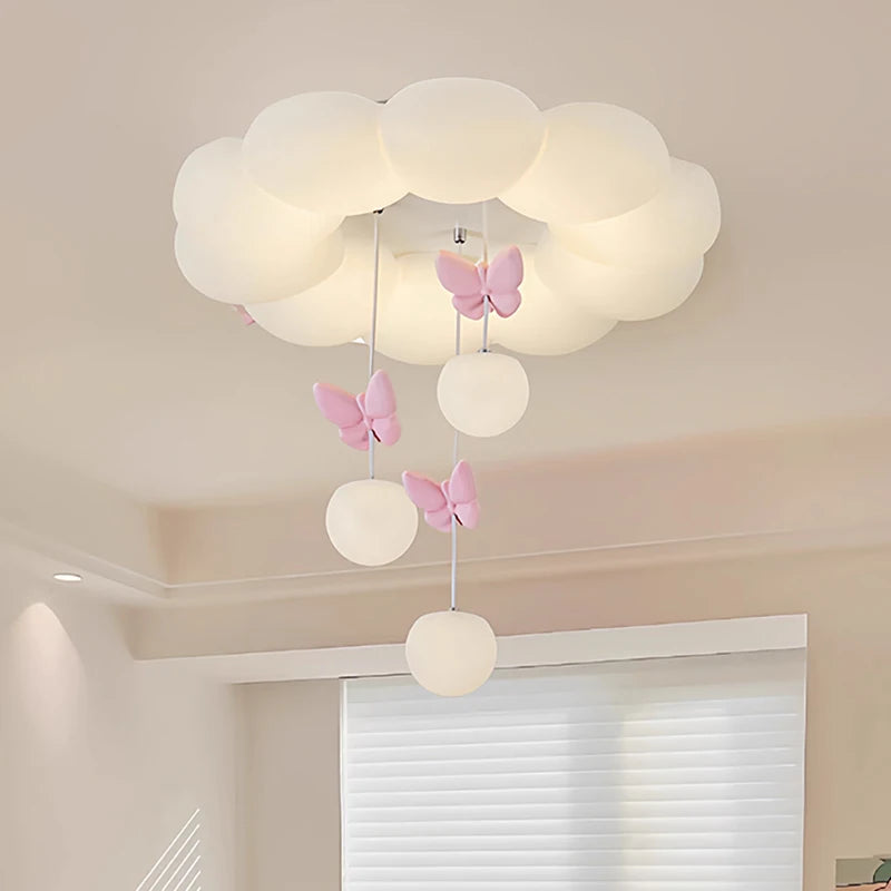White cloud-shaped ceiling light with pink butterflies and hanging glass orbs, illuminated.