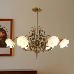 A polished copper floral chandelier with frosted rose-shaped glass shades, viewed from a side angle with artwork in the background.